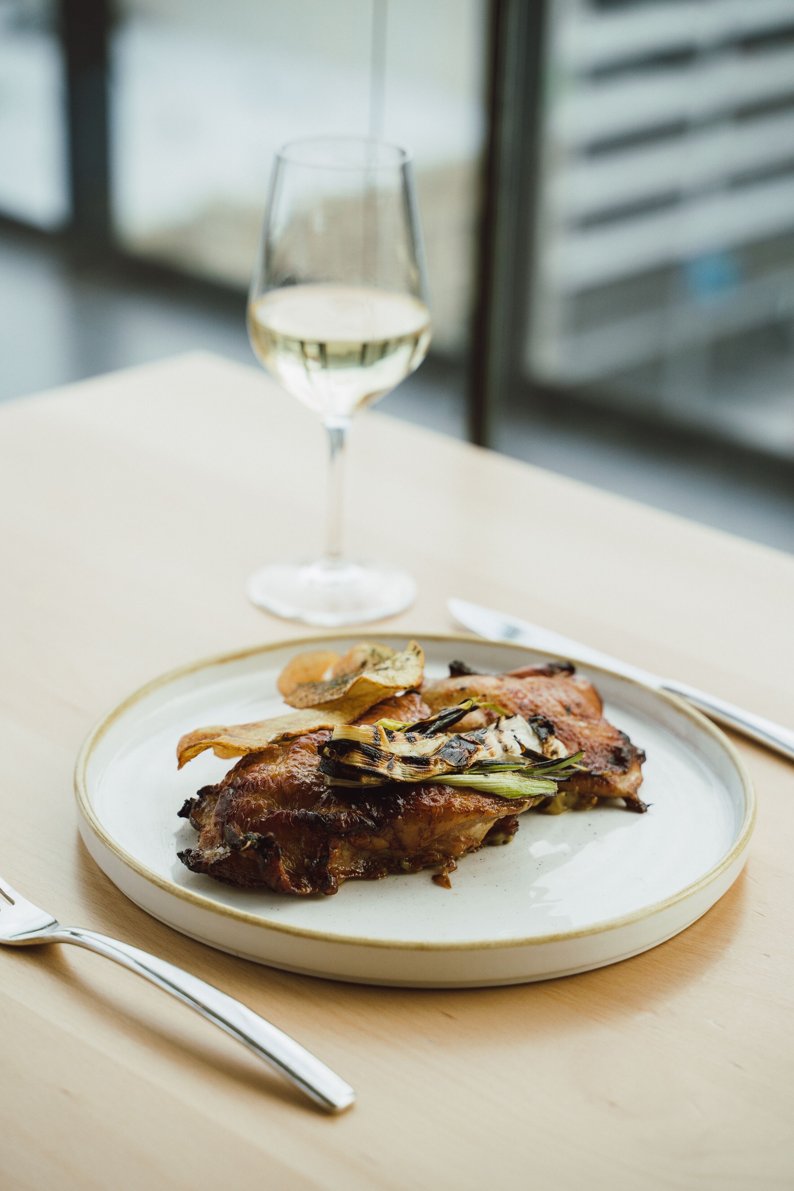A plate of food with a glass of white wine on a table.