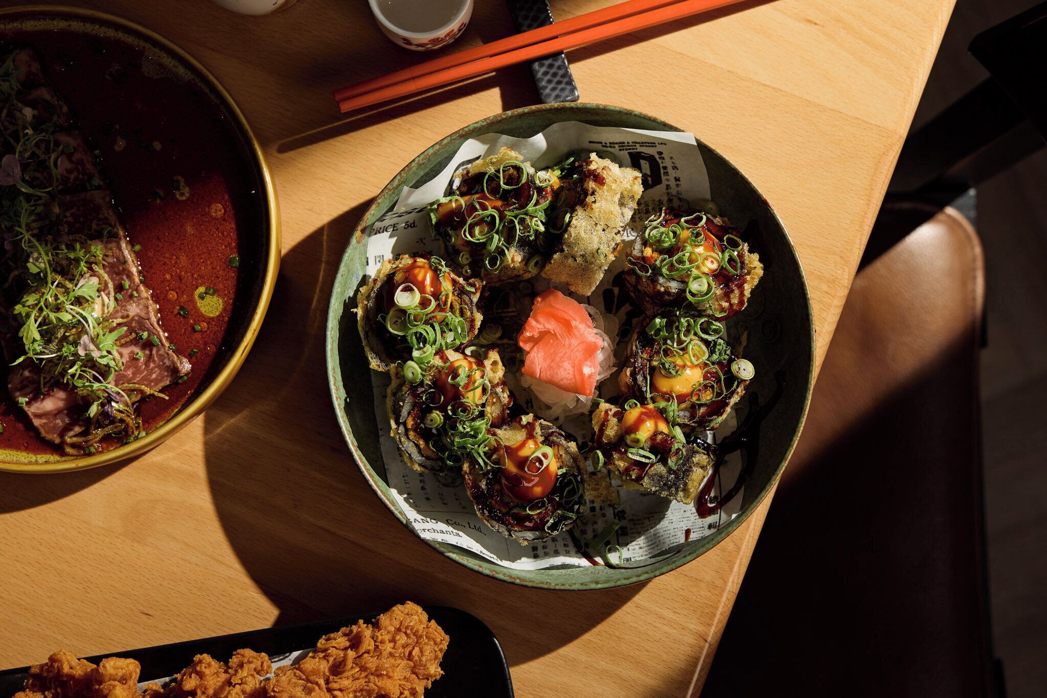 A dining table with a variety of dishes, including a bowl of soup, a plate of bread with toppings, and a plate of fried food.