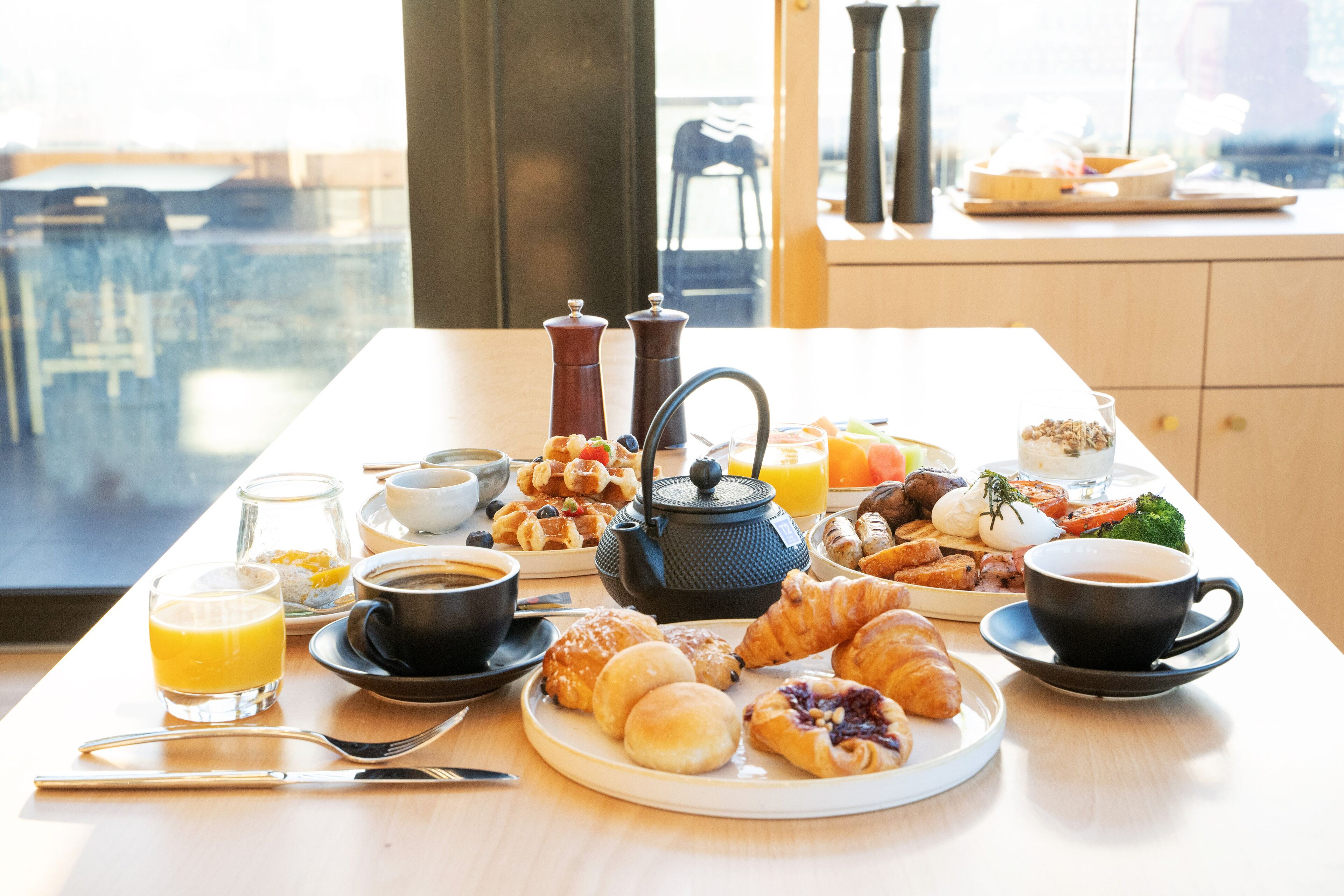A breakfast table with croissants, pastries, coffee, and juice.