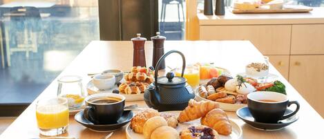 A breakfast table with croissants, pastries, coffee, and juice.