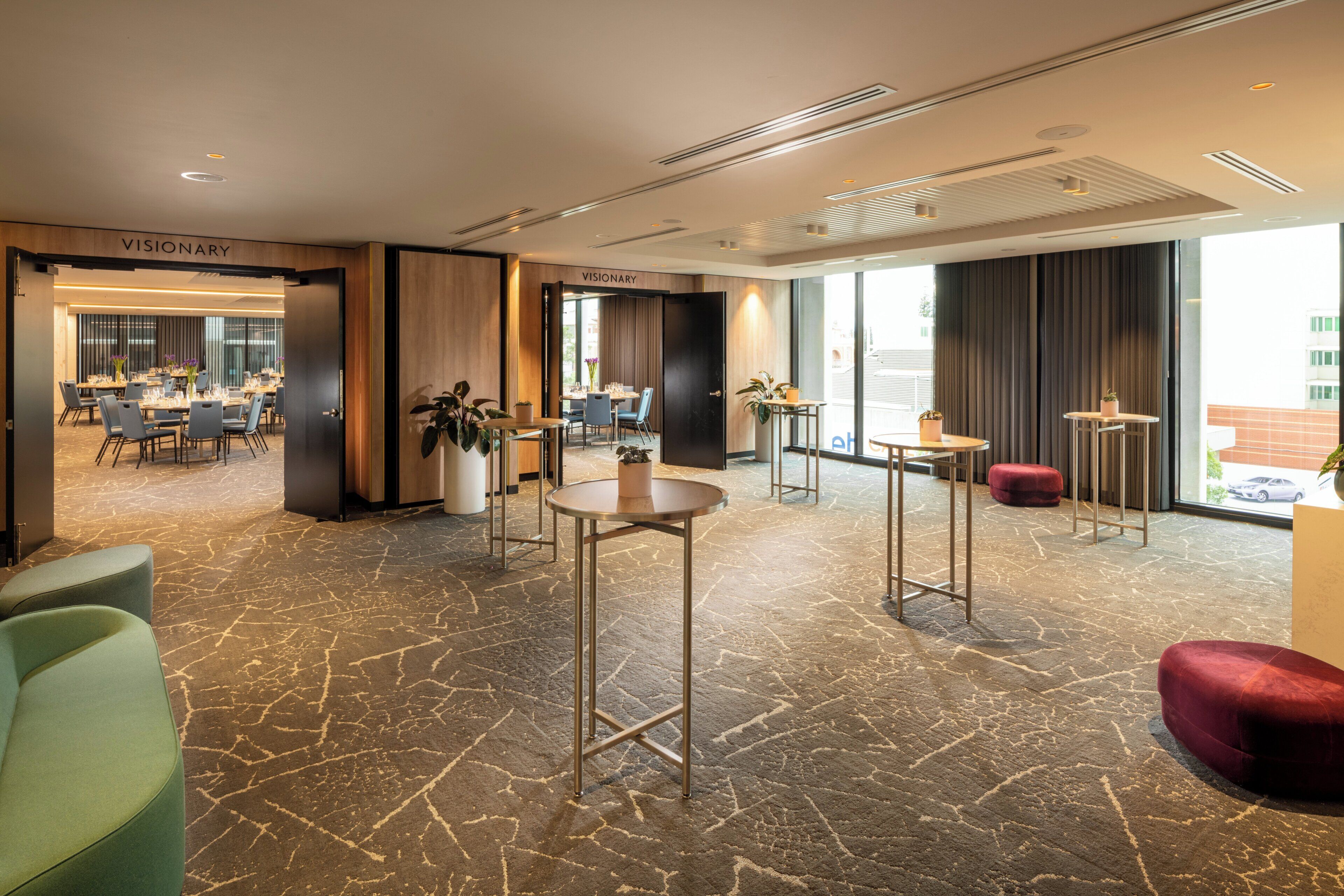 A hotel lobby with a reception desk, seating area, and a dining space.