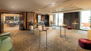A hotel lobby with a reception desk, seating area, and a dining space.