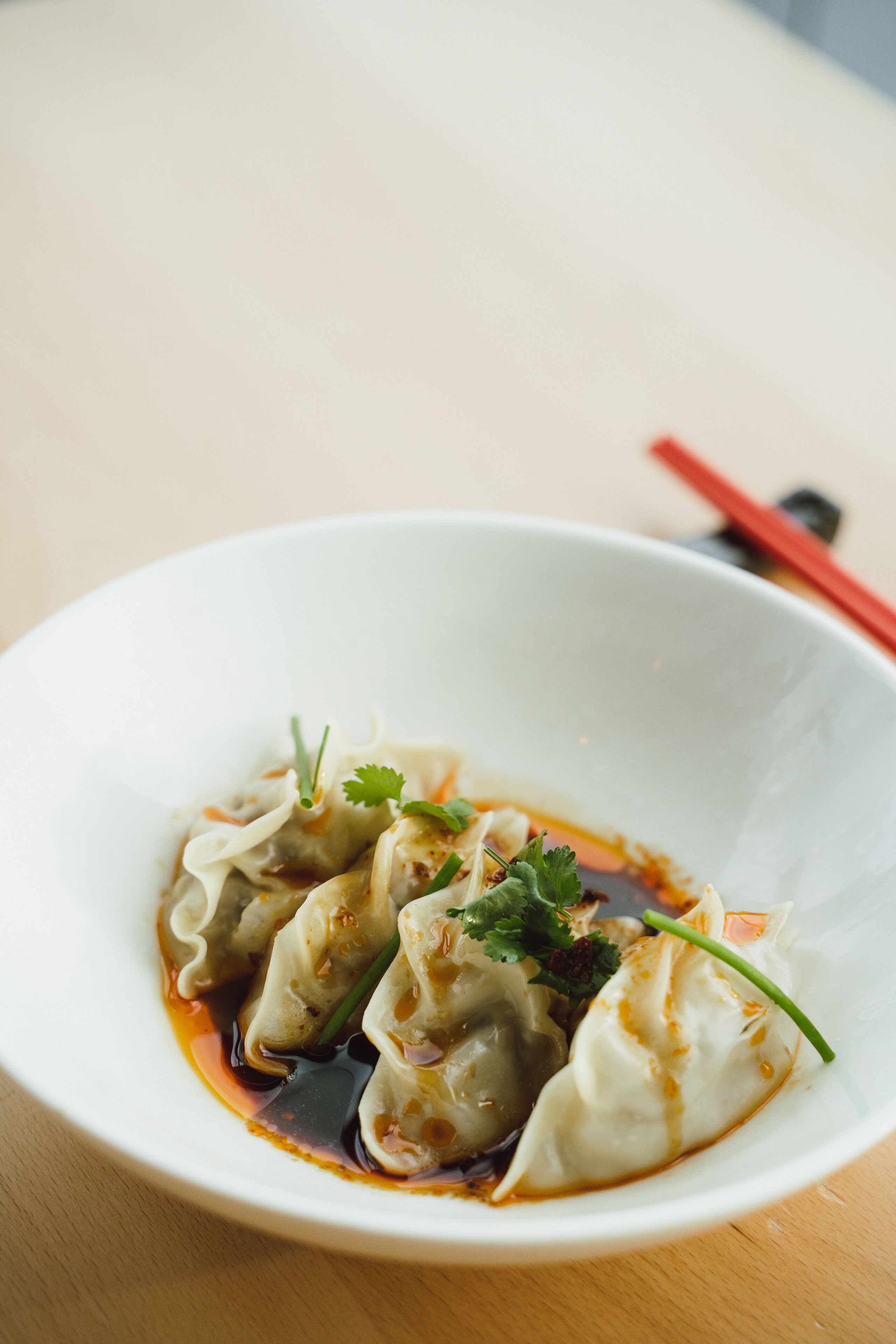 Un tazón de dumplings con salsa y decoración sobre una mesa de madera.