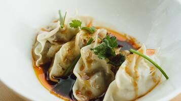 Un tazón de dumplings con salsa y decoración sobre una mesa de madera.