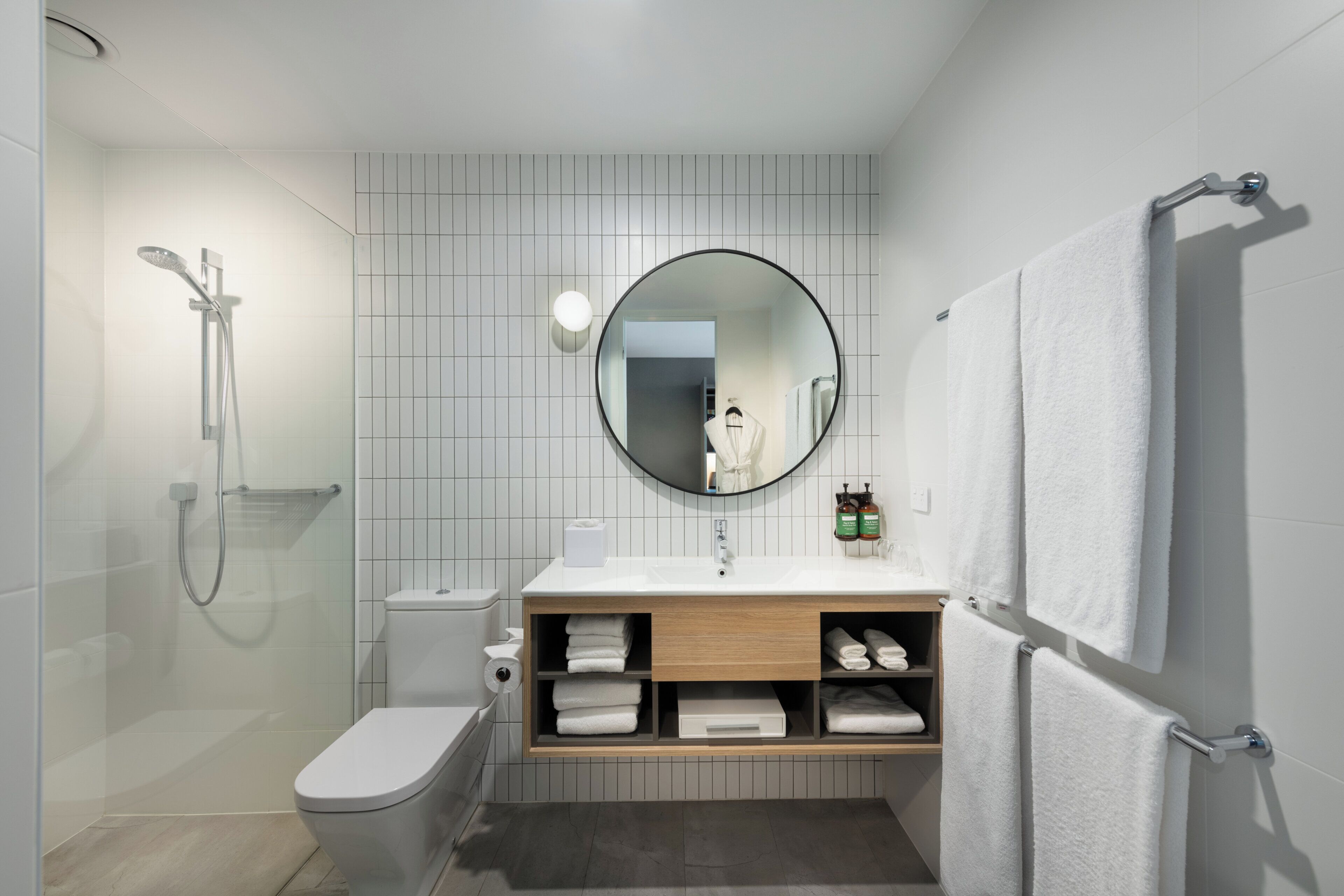Un baño moderno con ducha, inodoro, lavabo y espejo.