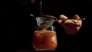 Una persona vertiendo un líquido en un vaso con un colador de metal.