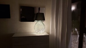 Ett nattduksbord med en lampa i glas och en svart lampskärm.