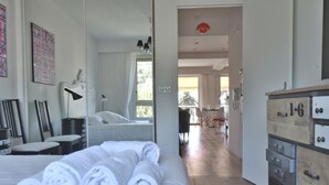 A bedroom with a bed, a dresser, and a view into the dining area. - 1-Br Apartment, Sea View, Steps from Beaches (Cannes)
