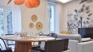 A modern dining area with a round wooden table, black chairs, and a grey sofa. - Modern 3-Br Apartment in City Center, 5 Minutes from Palais and Beache (Cannes)