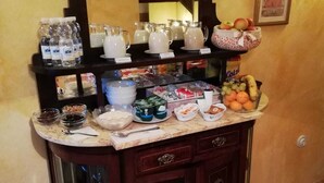 A buffet setup with various food and drink items, including fruits, beverages, and condiments. - Casa del Riu (Beneixama)