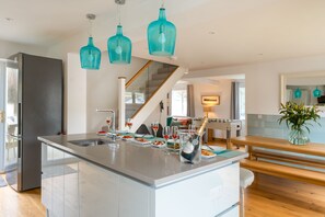 A modern kitchen with a central island, stainless steel appliances, and teal pendant lighting. - The Rock, Sleeps 8, Pets, Hot Tub (Braunton)