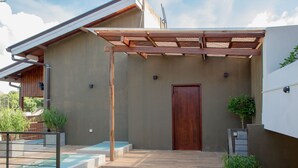 A modern building with a wooden door, a covered outdoor area, and a pool. - Sea Horse Hotel and Spa (Negombo)