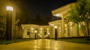 A large, well-lit building with a grand entrance and columns, surrounded by palm trees. - Sea Horse Hotel and Spa (Negombo)