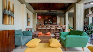 A spacious living area with modern furniture, a bar area with shelves of bottles, and a ceiling fan. - Sea Horse Hotel and Spa (Negombo)