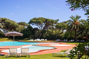 Relax by the serene pool surrounded by lush greenery and comfortable lounge chairs.