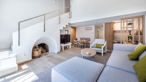 Una sala de estar moderna con chimenea, una escalera, un comedor y una zona de estar con sofá y sillones.