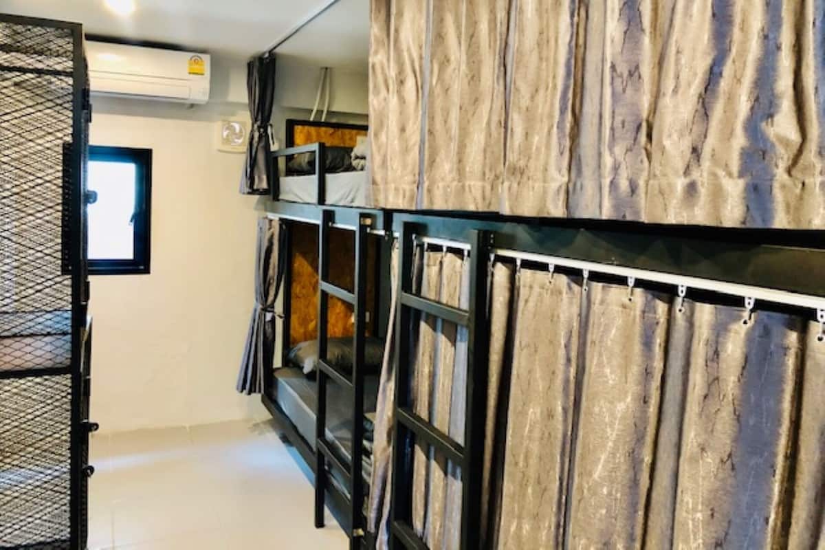 Ein kleines Zimmer mit Etagenbetten, einem Fenster und einer Klimaanlage.