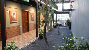 Un couloir d’hôtel avec un panneau indiquant la sortie de secours, des portes en bois et des œuvres d’art encadrées accrochées aux murs.