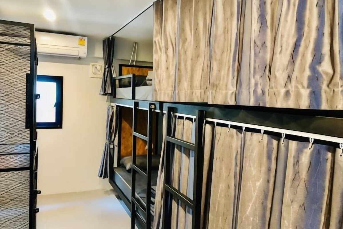 A compact hotel room with a bunk bed, a wardrobe with a wooden panel design, and a small window.