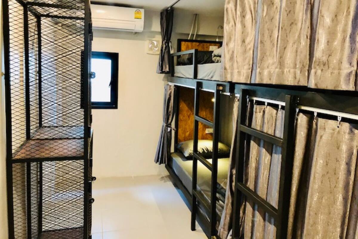 Ein kleines Zimmer mit Etagenbetten, einem Fenster und einer Klimaanlage.