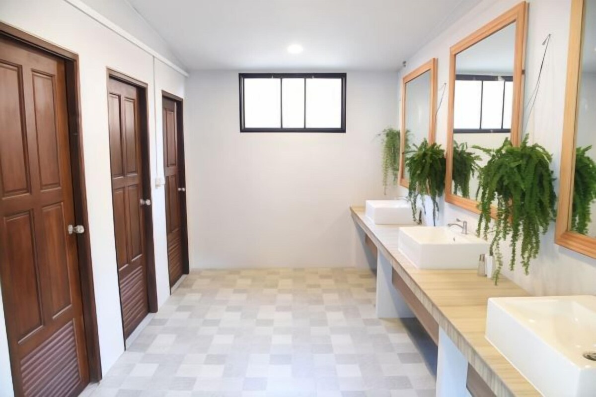 A bathroom with three sinks, wooden doors, and a window.