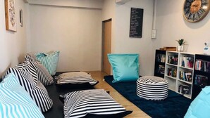 Un coin salon confortable avec des coussins à rayures et une bibliothèque remplie de livres.