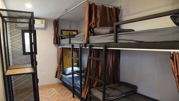 A bunk bed room with a metal ladder, a herringbone-patterned floor, and a window with curtains.