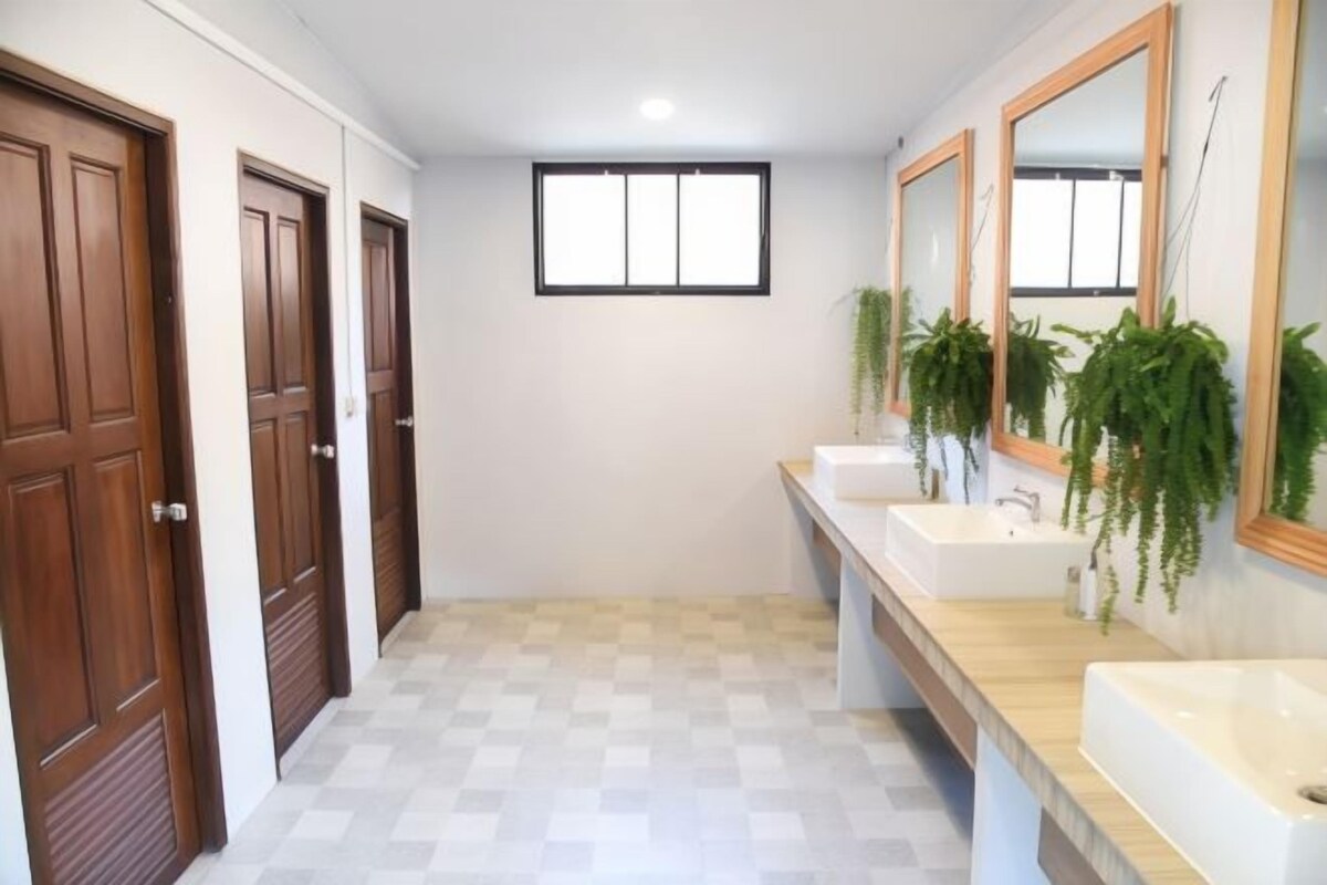 A bathroom with two sinks, wooden doors, a window, and potted plants.