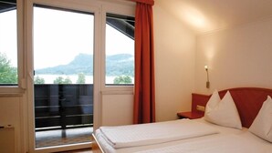 A hotel room with two beds, a view of a lake, and a balcony with a red curtain.