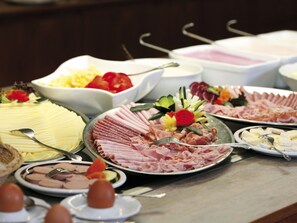 Een buffet met diverse soorten eten, zoals vleesschotels, kazen en groenten.