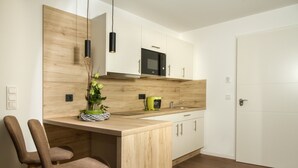 Eine moderne Küche mit Holzschränken, einer eingebauten Mikrowelle und einer Kochinsel mit Stühlen.