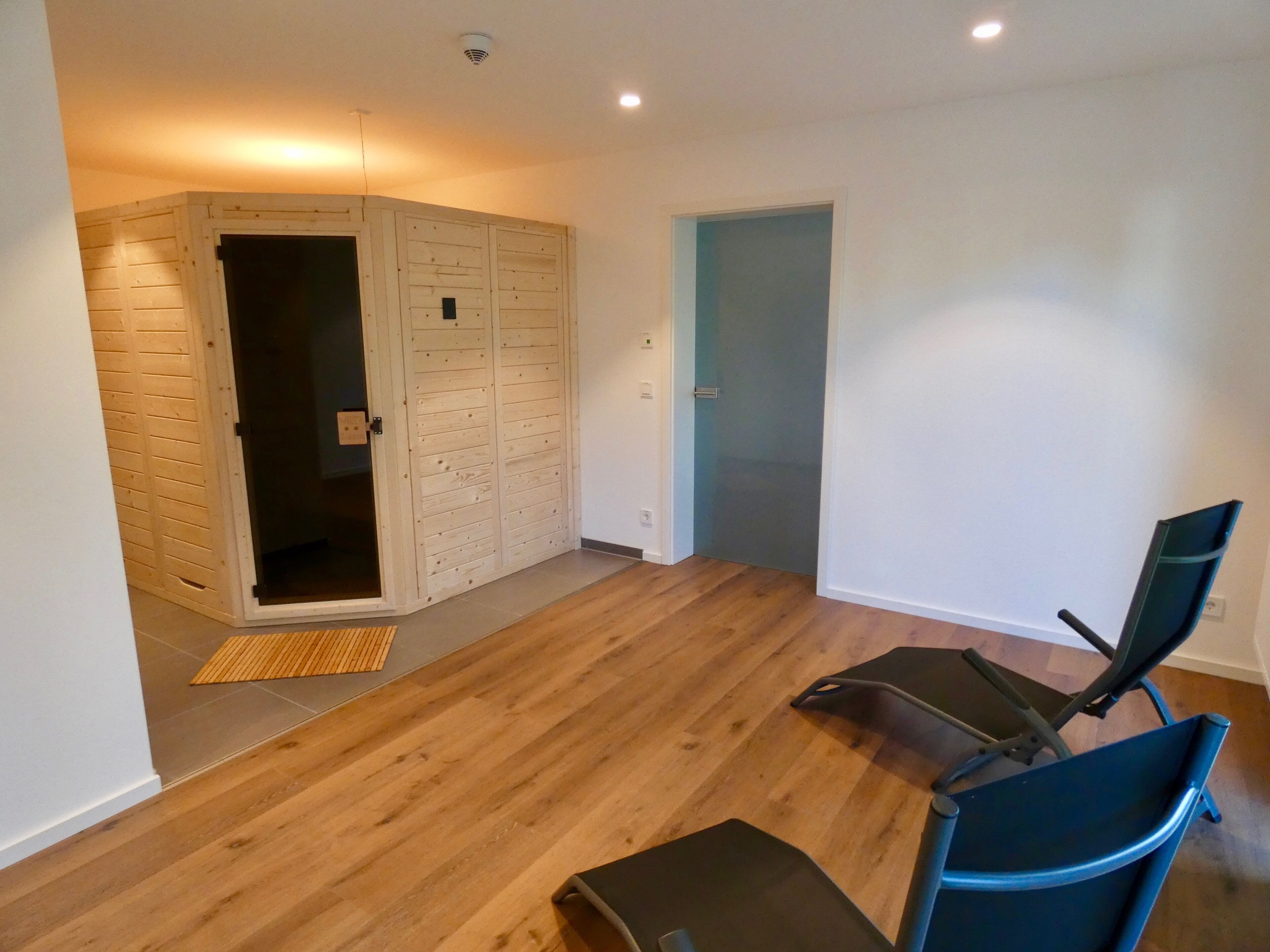 Ein Zimmer mit Holzboden, einer blauen Tür und einem Stuhl.