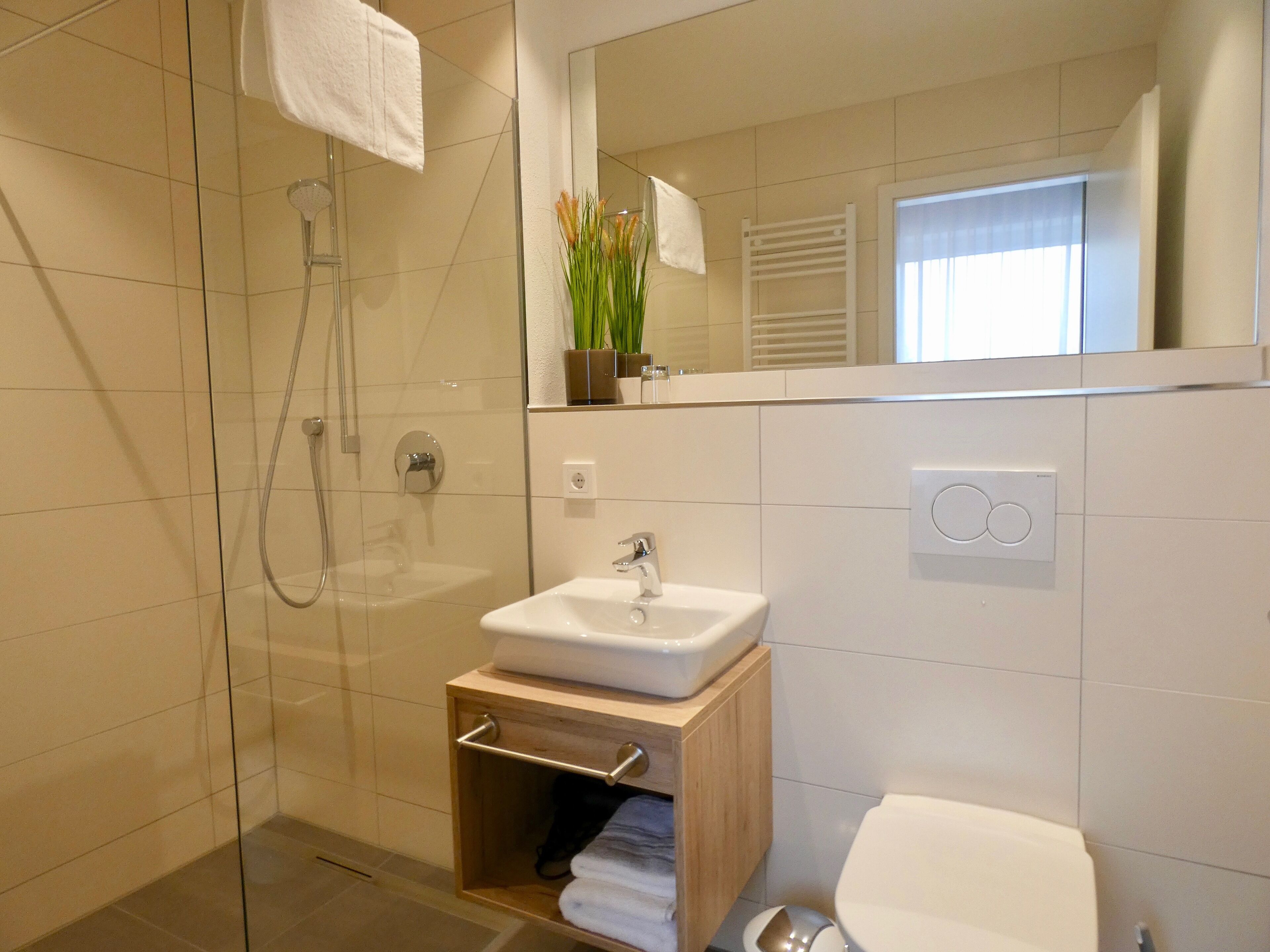 Un baño moderno con cabina de ducha de vidrio, un lavamanos blanco y un inodoro.