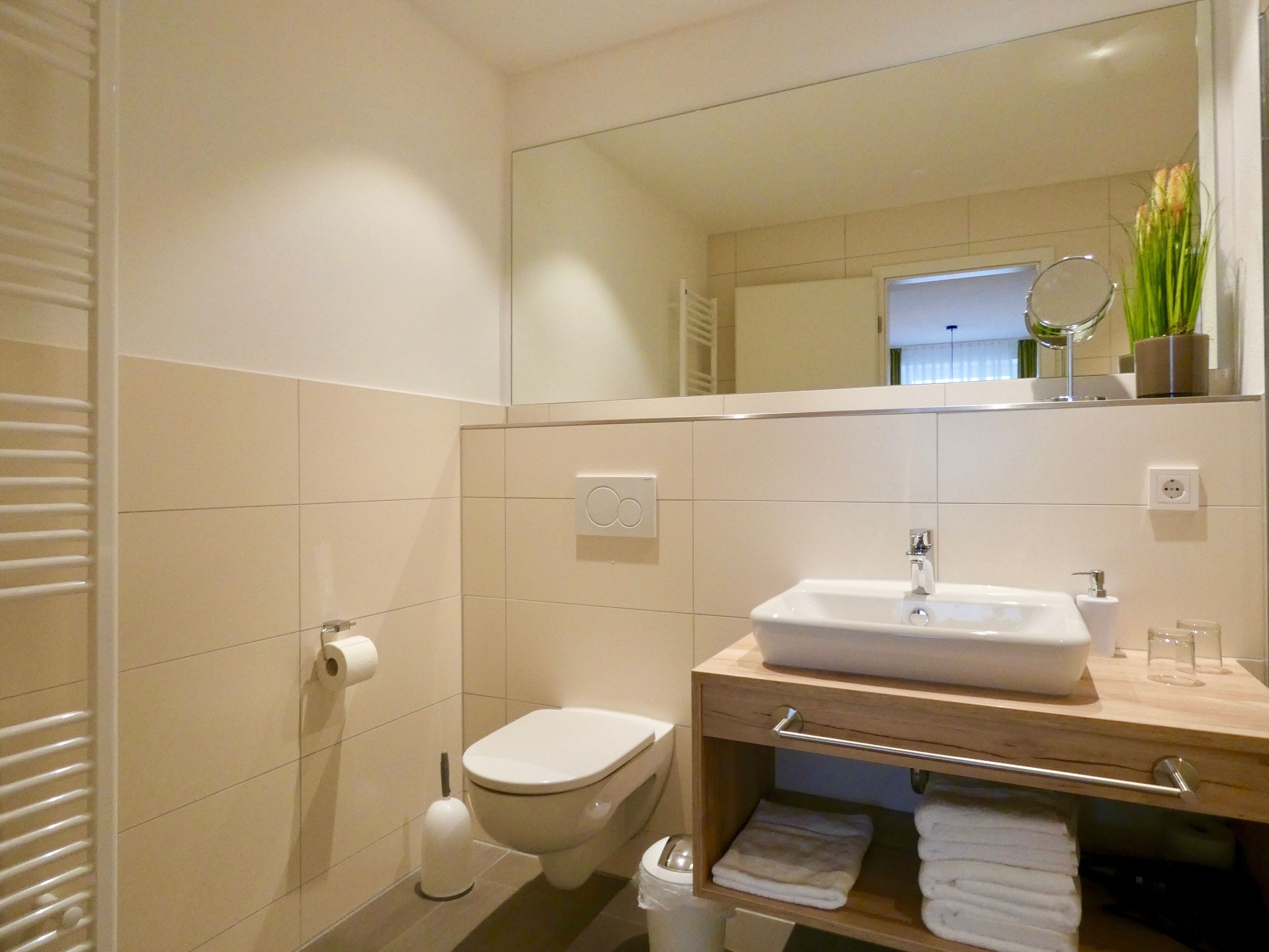 A modern bathroom with a toilet, sink, and mirror.