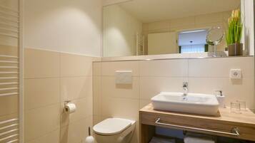 A modern bathroom with a toilet, sink, and mirror.
