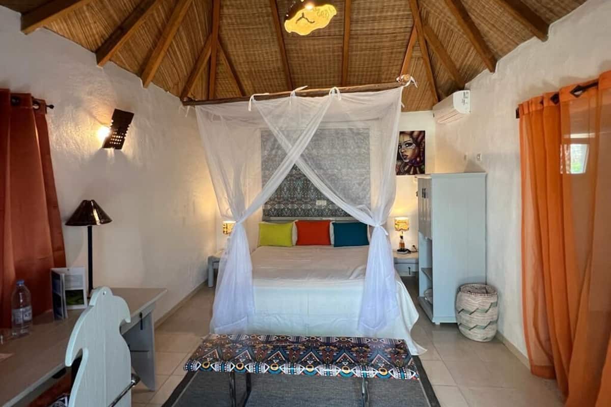 Une chambre à coucher avec un lit sous un dais, une table de chevet, une lampe et un petit bureau avec une chaise.