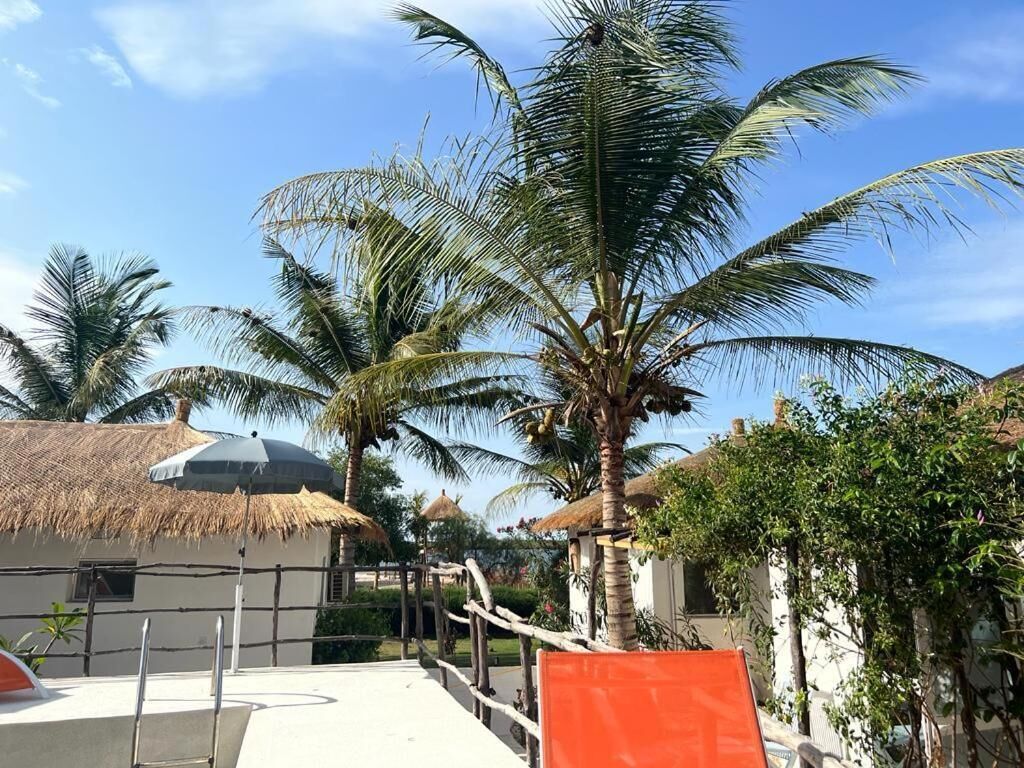 Un resort tropical con palmeras, edificios de techo de paja y cielo despejado.