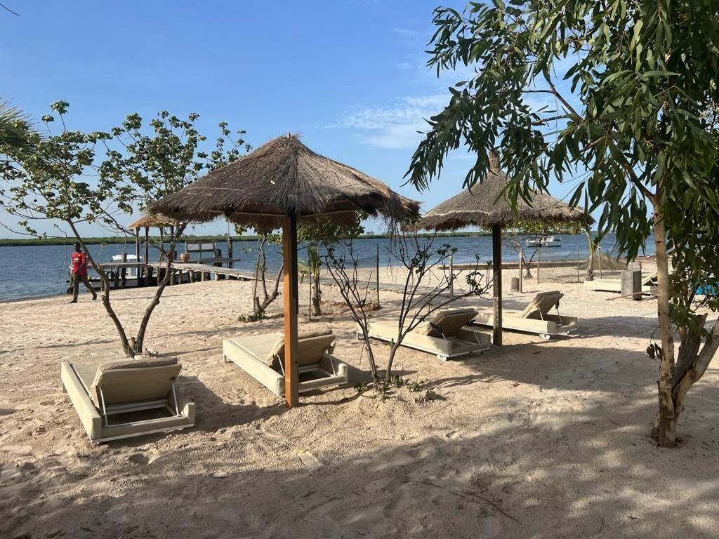 A beach with thatched umbrellas and lounge chairs.