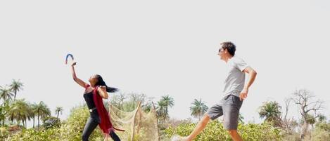 Two people playing a sport on a beach with palm trees and a clear sky.