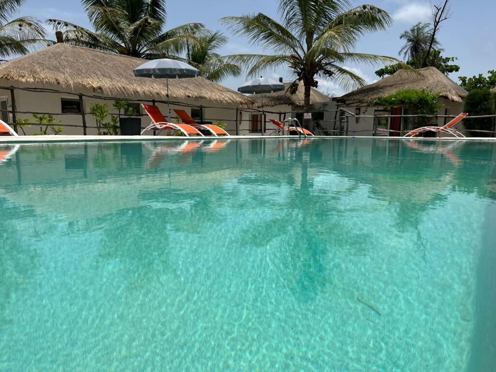 A clear swimming pool with lounge chairs and thatched-roof structures.