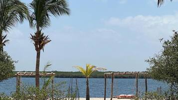 A beach with palm trees, a wooden structure, and a view of the water.