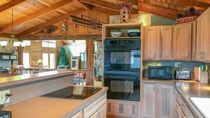 Een keuken in chaletstijl met een grote kookplaat, magnetron en houten kastjes.
