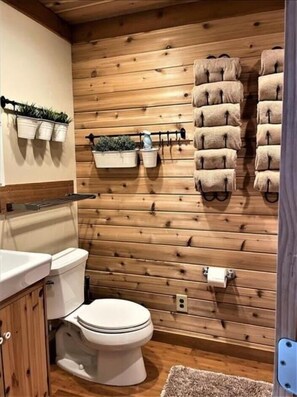 Un bagno con rivestimento in legno, dotato di un water, un lavabo e un portasciugamani.