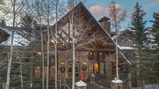 Eine Lodge mit einer Steinfassade, Holzbalkonen und einem verschneiten Eingangsbereich.
