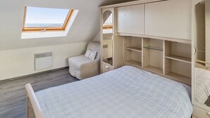 A bedroom with a skylight, a bed, a chair, and built-in storage.