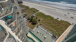 A beachfront hotel with a pool area, beach access, and a view of the ocean.