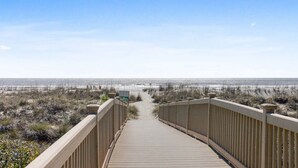 A wooden boardwalk leading to a beach with a clear view of the ocean.