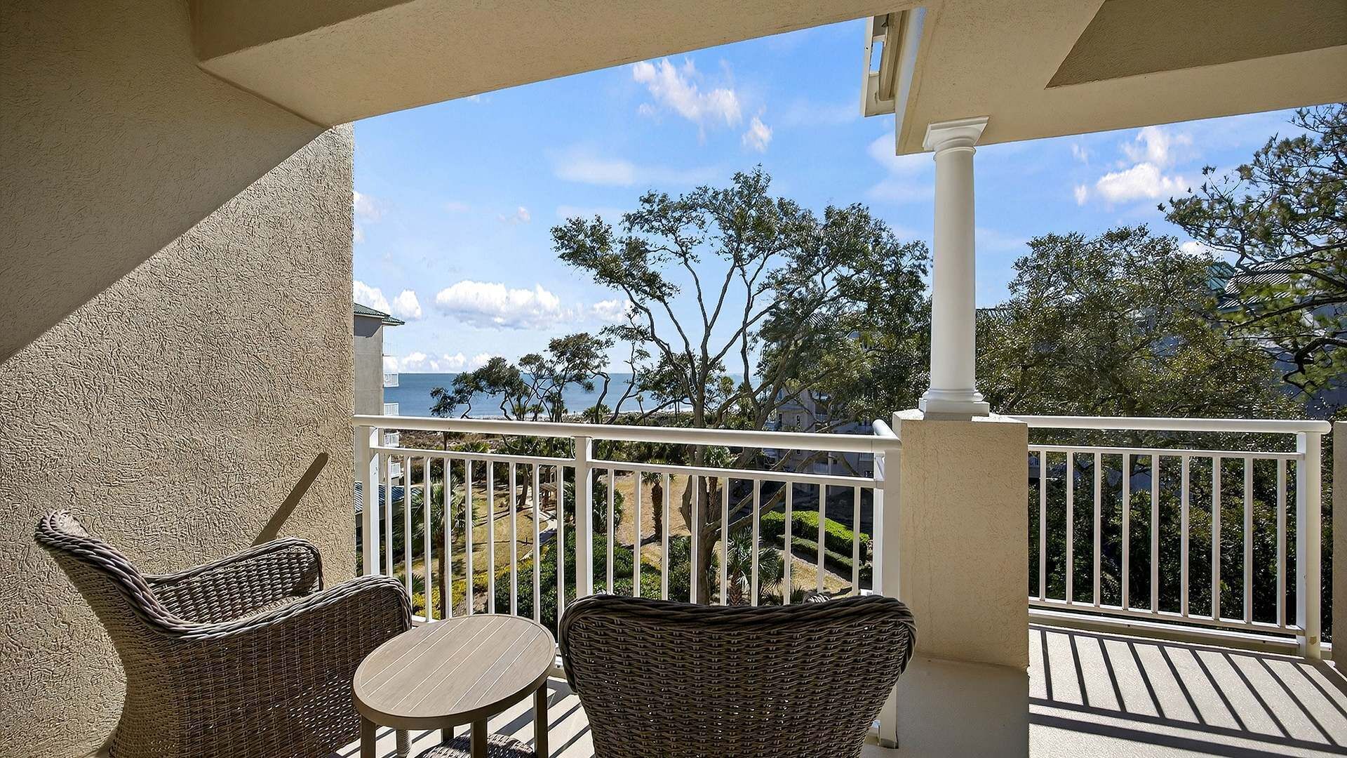 A balcony with wicker furniture and a view of the ocean.