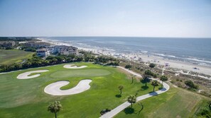 Un parcours de golf doté de bunkers, bordé d’une plage et offrant une vue sur l’océan.