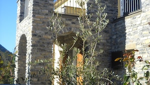 A stone building with a balcony and a metal fence in the foreground. - Agriturismo Mamma Chica (La Spezia)